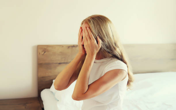 istock Upset sad crying middle-aged woman covering her eyes with her hands while experiencing mental or physical suffering sitting on bed at home 1706430174