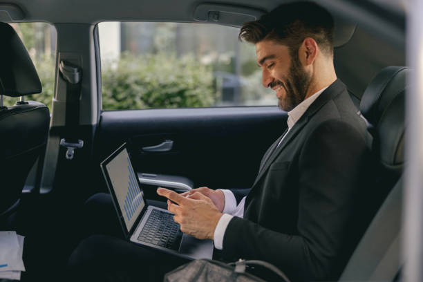 istock Smiling entrepreneur working on laptop and use mobile phone while going to airport by car 1706430741