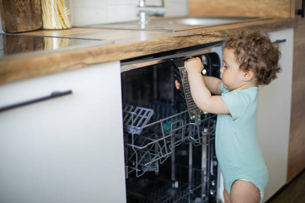 istock Baby toddler is standing by an open dishwasher with dirty dishes inside 1706443149