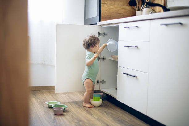 귀여운 호기심 많은 백인 아기가 부엌에서 찬장 문을 열고 콘텐츠를 탐색한다 - domestic kitchen accessibility open drawer 뉴스 사진 이미지