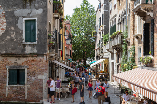 Venice, Italy, July 15, 2016; Cozy narrow street with eateries and shops in the center of Venice in Italy.