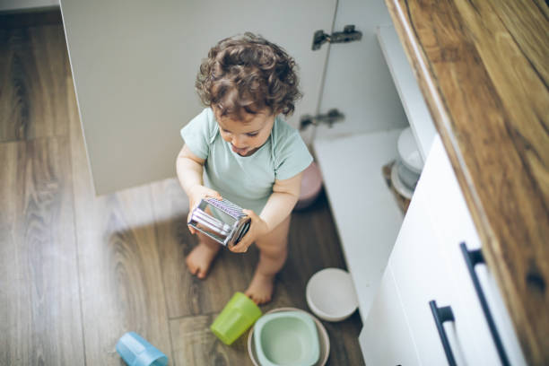 милый ребенок играет с кухонной утварью на домашней кухне - domestic kitchen accessibility open drawer стоковые фото и изображения