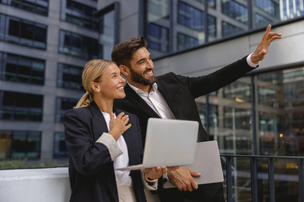 istock Two business colleagues working on project while sitting outdoors on skyscrapers background 1706451875