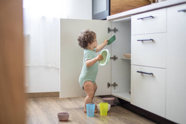 милый ребенок играет с кухонной утварью на домашней кухне - domestic kitchen accessibility open drawer стоковые фото и изображения