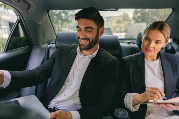 istock Smiling business analysts have online meeting using laptop while sitting in car back seats 1706457624