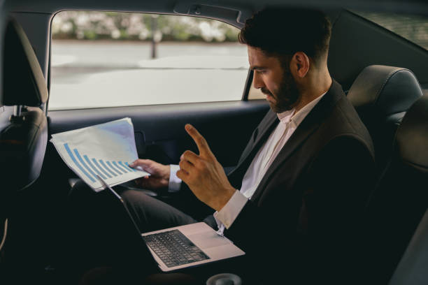 istock Confidence businessman sitting on car backseat and working with documents and use laptop 1706458303
