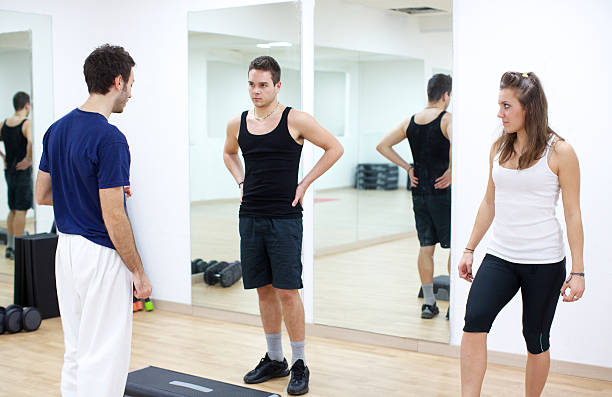 istock Trainer assisting a couple in the gym 170646082