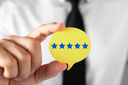Five star rating on speech bubble shaped card holding by a businessman