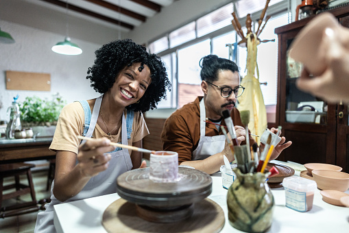 Portrait of a mid adult woman painting pottery in a ceramics workshop