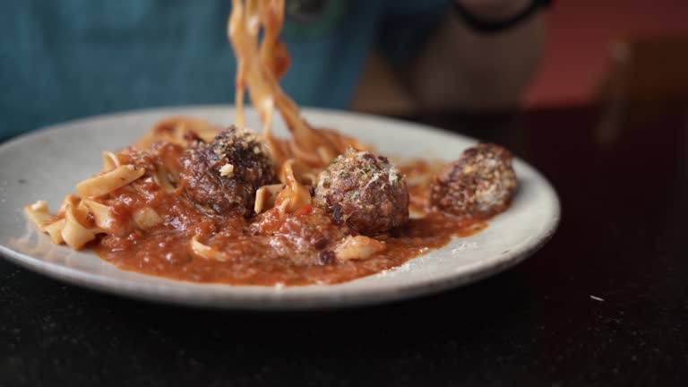 Man eating spaghetti and beef Meatballs with tomato sauce in Italian restaurant