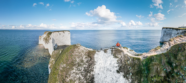 Hiker at the famous Old Harry Rocks, the most eastern point of the Jurassic Coast, a UNESCO World Heritage Site, UK. Evening golden hour