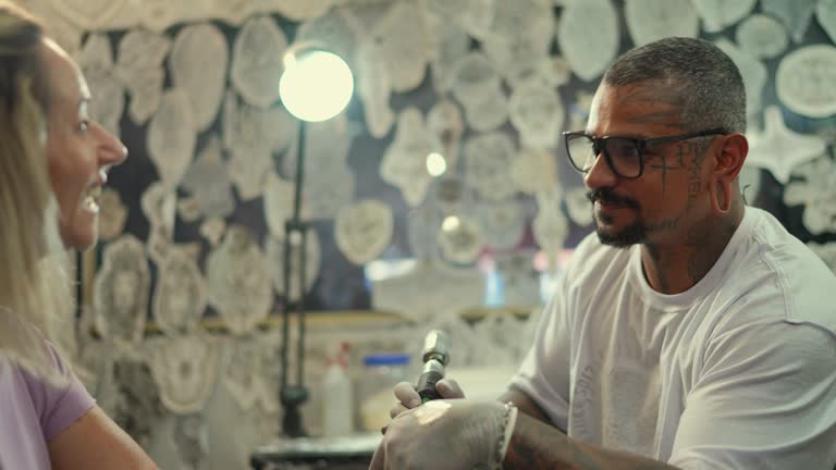 Tattoo artist tattooing a woman's arm at a tattoo studio