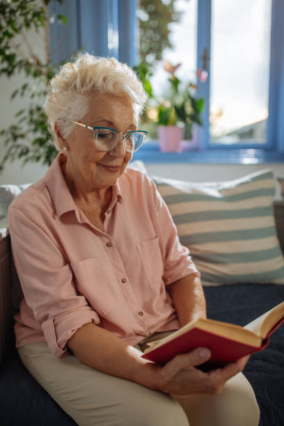 istock Happy elderly woman reading a book at home 1706642266