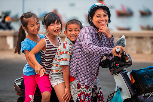 Vietnamese mother with her three children riding a motorbike, South Vietnam