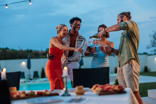 istock Guy is pouring champagne for his friends at a poolside dinner party 1706653169