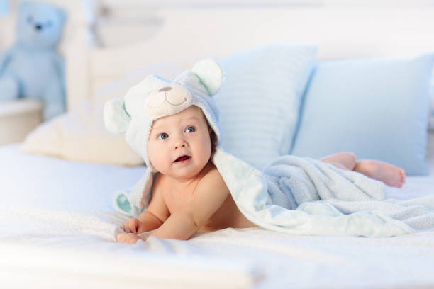 istock Baby boy in blue towel on white bed 1706660345