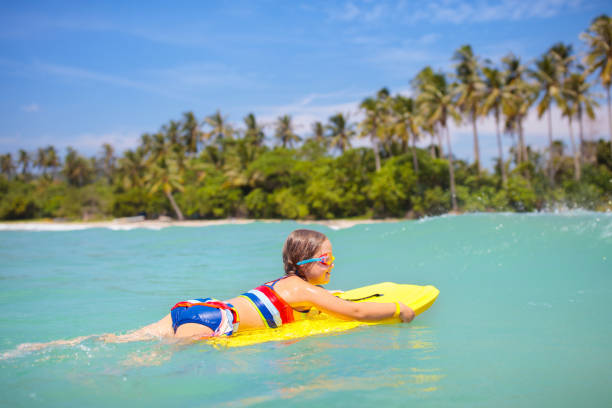 istock Child surfing on tropical beach. Surfer in ocean. 1706667098
