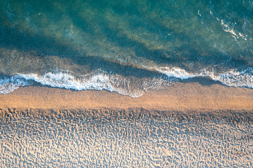 Drone view of sandy beach with sea waves