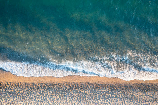 Drone view of sandy beach with sea waves
