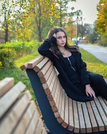 A beautiful girl posing on a bench in an autumn park