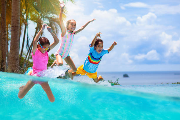 Kids jump into swimming pool. Summer water fun. Group of kids jump into swimming pool. Summer water fun. Children play in outdoor pool. Summer family vacation with young kid. Holiday in tropical resort. Travel with child. game resort pictures stock pictures, royalty-free photos & images