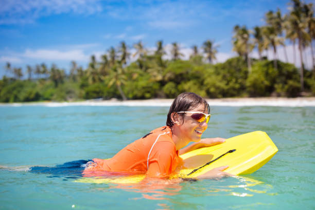 istock Child surfing on tropical beach. Surfer in ocean. 1706713045