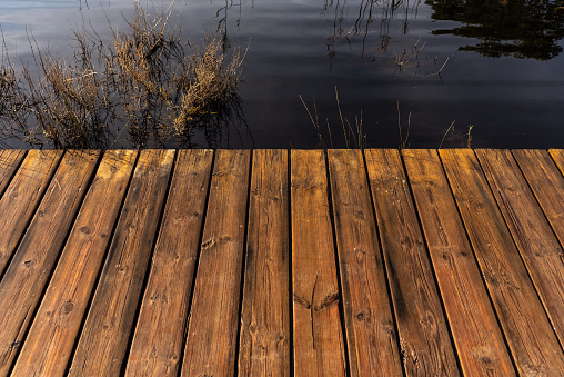 Tables of a wet wooden bridge over a lake.