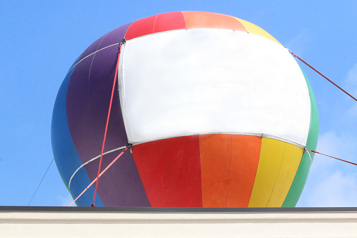 This beautiful colorful hot air balloon is tethered for rides at the first annual Taste N Glow Festival in Wausau, Wisconsin on July 10, 2021.  The vivid blue sky has white clouds.