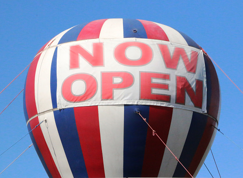 a red white and blue hot air balloon saying Now Open
