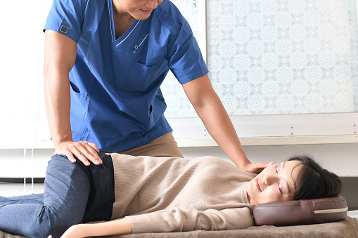Asian chiropractor giving leg massage and Asian woman receiving treatment