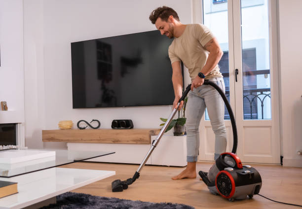 man using vacuum to clean the living room - appliance living room domestic room lifestyles imagens e fotografias de stock