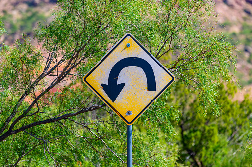 A weathered, chipped street sign directing people to turn around.