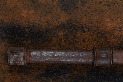 Rusty plumb tube on rusty metal wall background