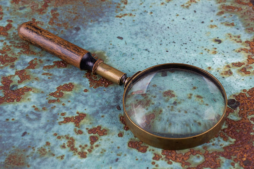 Vintage magnifying glass on rusty metal surface coated with corrosion.