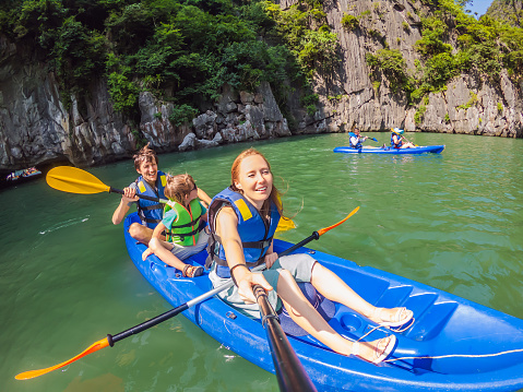 Mom, dad and son travelers rowing on a kayak in Halong Bay. Vietnam. Travel to Asia, happiness emotion, summer holiday concept. Traveling with children concept. After COVID 19. Picturesque sea landscape. Ha Long Bay, Vietnam.