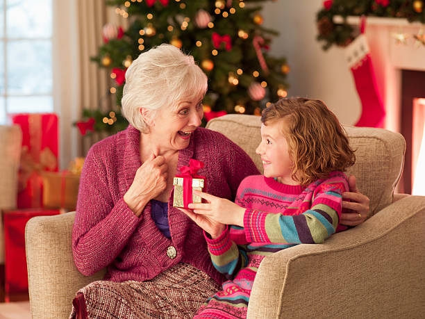 ragazza e la nonna tiene regalo di natale - grandmother giving gift child foto e immagini stock