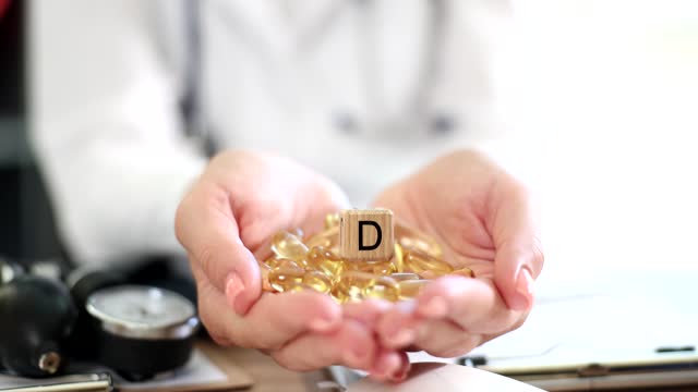 Yellow capsules of vitamin D in the hands of a doctor