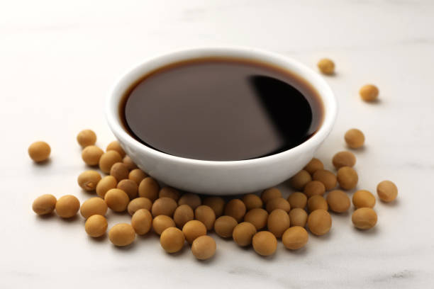 istock Soy sauce in bowl and soybeans on white table, closeup 1706974286