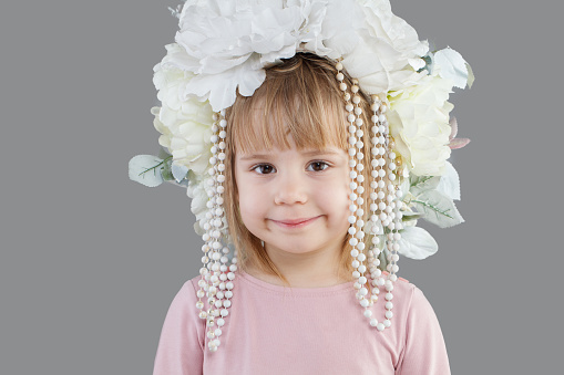 Cheerful smiling child baby girl in white flower hat closeup portrait