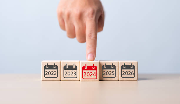 Year 2024 strategy target planning. Business goal in new year. Annual plan and highlight idea. Hand pushing wooden cubes with focusing red calendar and number 2024. Starting new start up in next year.
