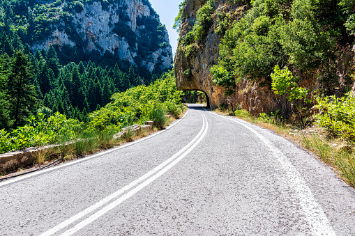 The gorgeous road under the rocks in the old Sparta-Kalamata highway in Peloponnese, Greece. This road connects two historic cities, Sparta and Kalamata, and offers breathtaking views of the Taygetos mountain range and the surrounding countryside.