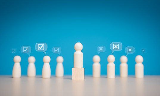 Open-mindedness or public hearing. Wooden figures peg dolls stand above wooden cube among others with vote yes or no symbol. Elections, Volunteers, Voting candidates, Constituency electorates concept.