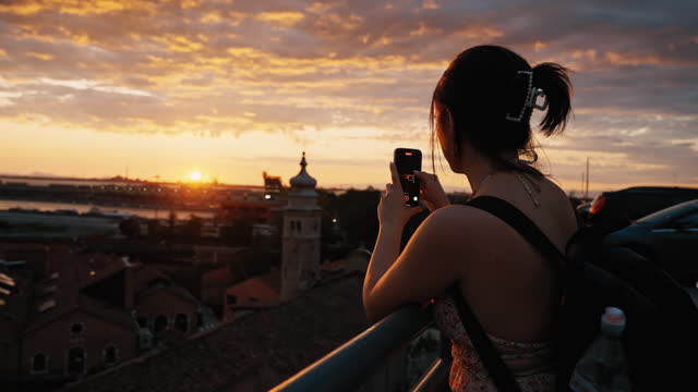 SLO MO Young Female Tourist Photographing Beautiful Sunset over Cityscape with Smartphone in Venice