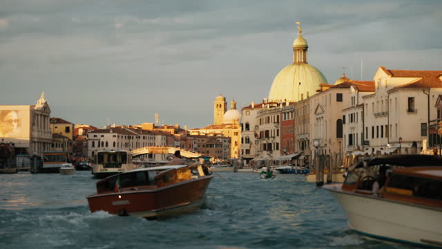 SLO MO Tourboats Navigating On Grand Canal amidst Historic Buildings in Venice under Cloudy Sky