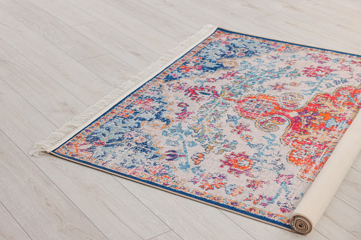 Wide angle color image depicting the interior of a bedroom. The room is decorated beautifully with rugs and ornaments, but the overall feel is light and airy. Light is streaming in from the windows, giving a bright happy feel.