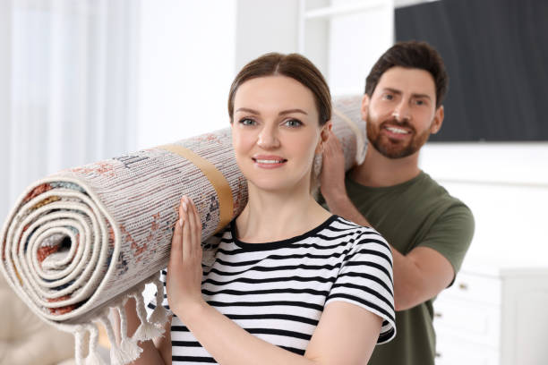 istock Smiling couple holding rolled carpet in room 1707081176