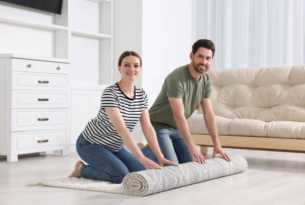 istock Smiling couple unrolling carpet with beautiful pattern on floor in room 1707081244