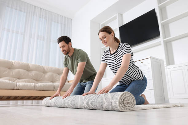 istock Smiling couple unrolling carpet with beautiful pattern on floor in room 1707081712