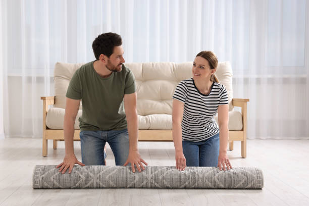 istock Smiling couple unrolling carpet with beautiful pattern on floor in room 1707081714