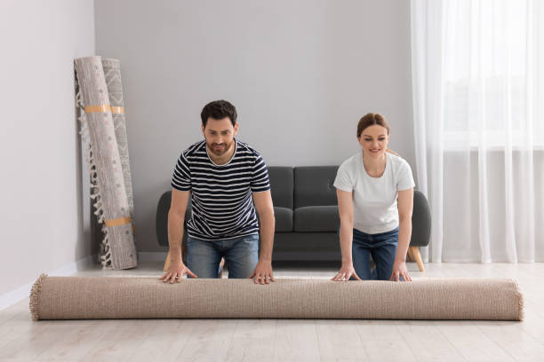 istock Smiling couple unrolling carpet on floor in room 1707082168